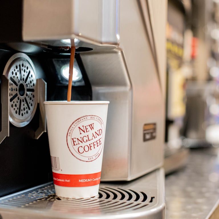 cup of new england coffee in automated coffee machine with coffee pooring in